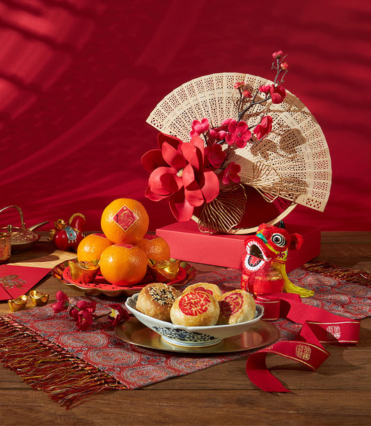 Mandarin oranges, Chinese pastries, and gold accents arranged for Chinese New Year gifting