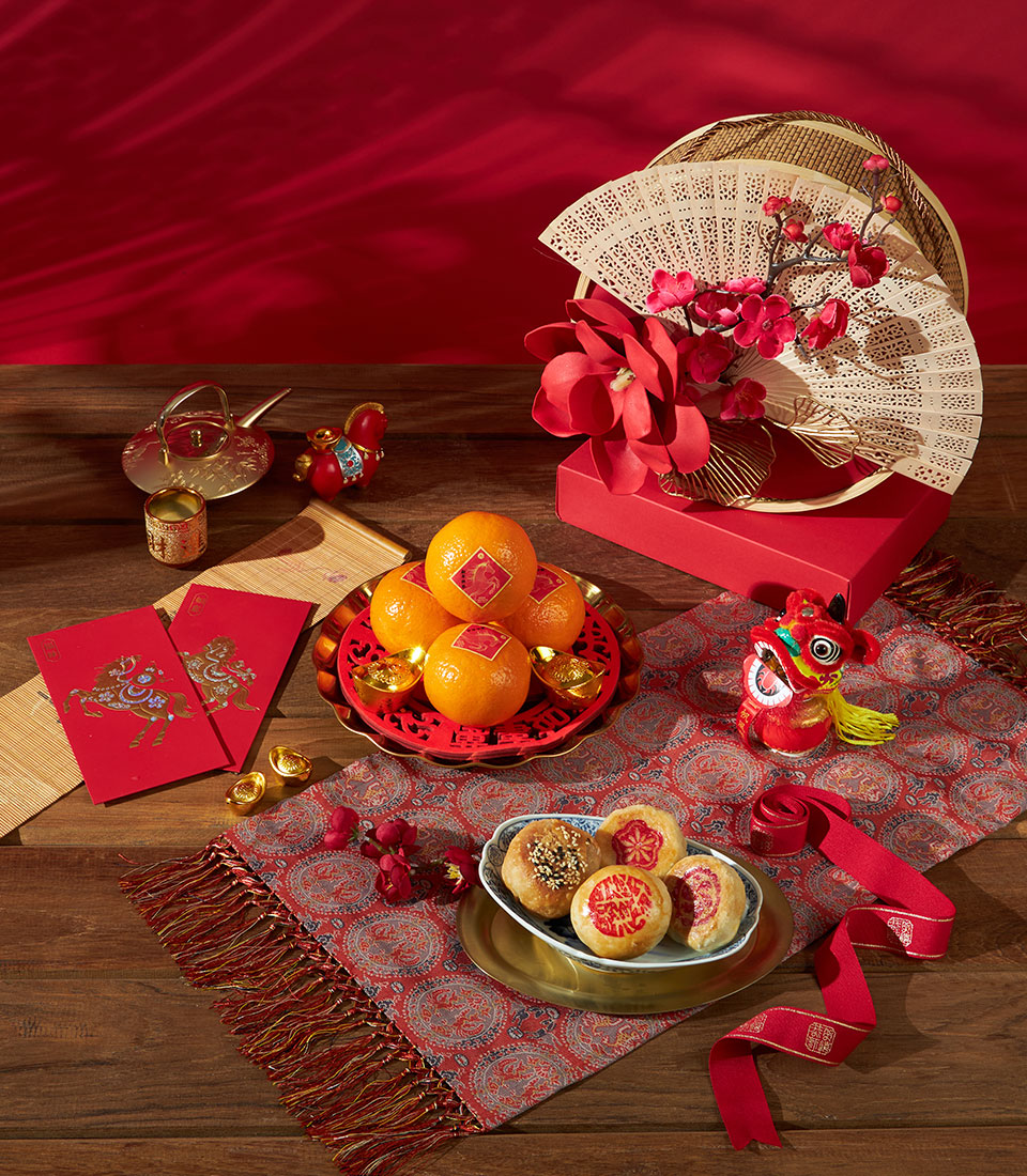 Mandarin oranges and traditional pastries Chinese New Year gift set with red envelopes, gold ingots, and festive decorations