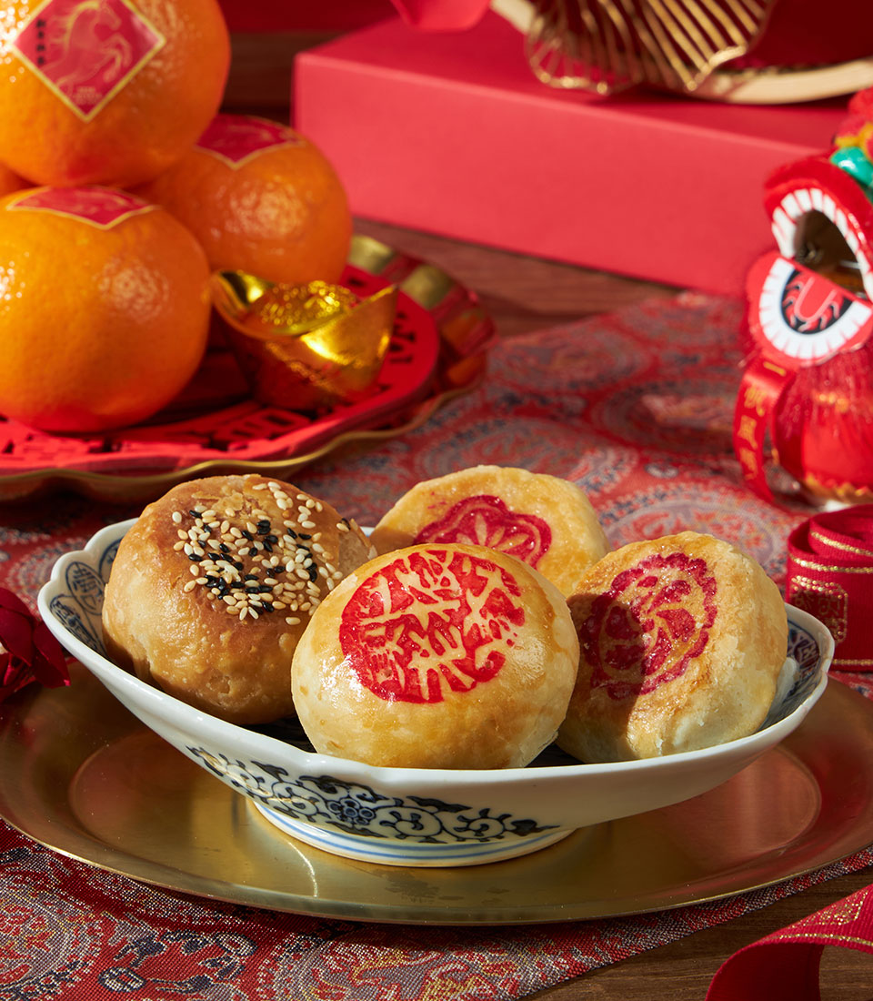 Festive Chinese New Year gift set with traditional pastries, mandarins, and gold accents in luxury hamper