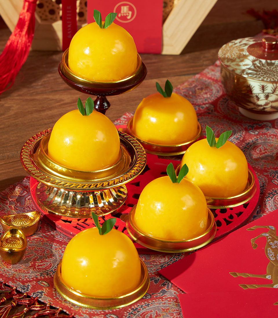 Mandarin & creamy mandarin dome cakes gift set, golden yellow with mint leaf tops, presented on red festive fabric with