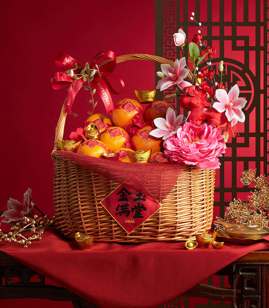 Festive wicker basket filled with mandarin oranges, gold ingots, and pink peonies for Chinese New Year prosperity gifting