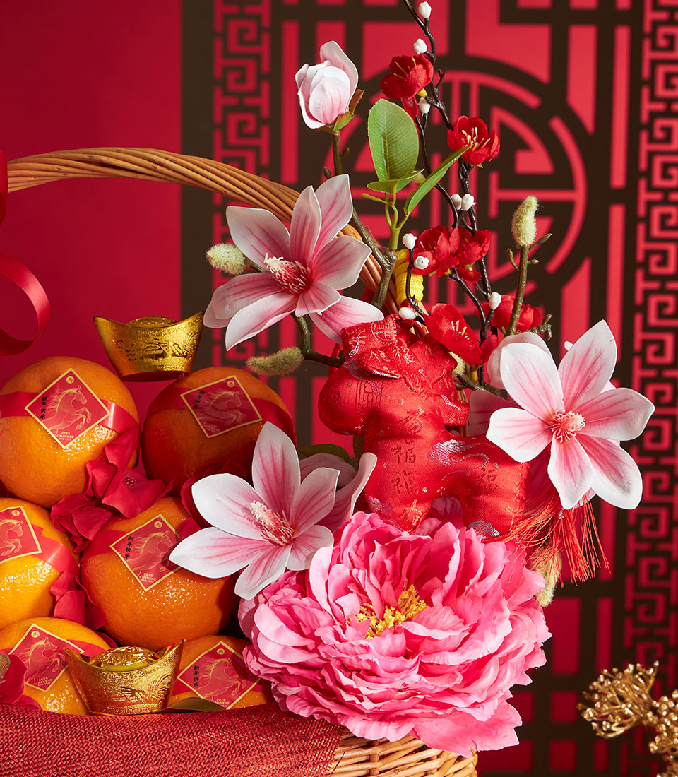 Red wicker basket with mandarin oranges, golden ingots, and pink peonies for Chinese New Year prosperity