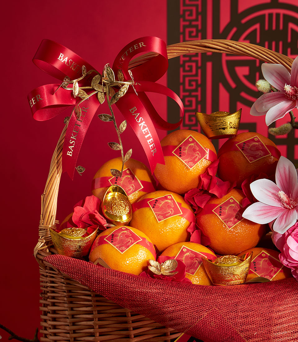 Woven wicker basket overflowing with mandarin oranges, golden ingots, and red silk ribbons for Chinese New Year prosperity