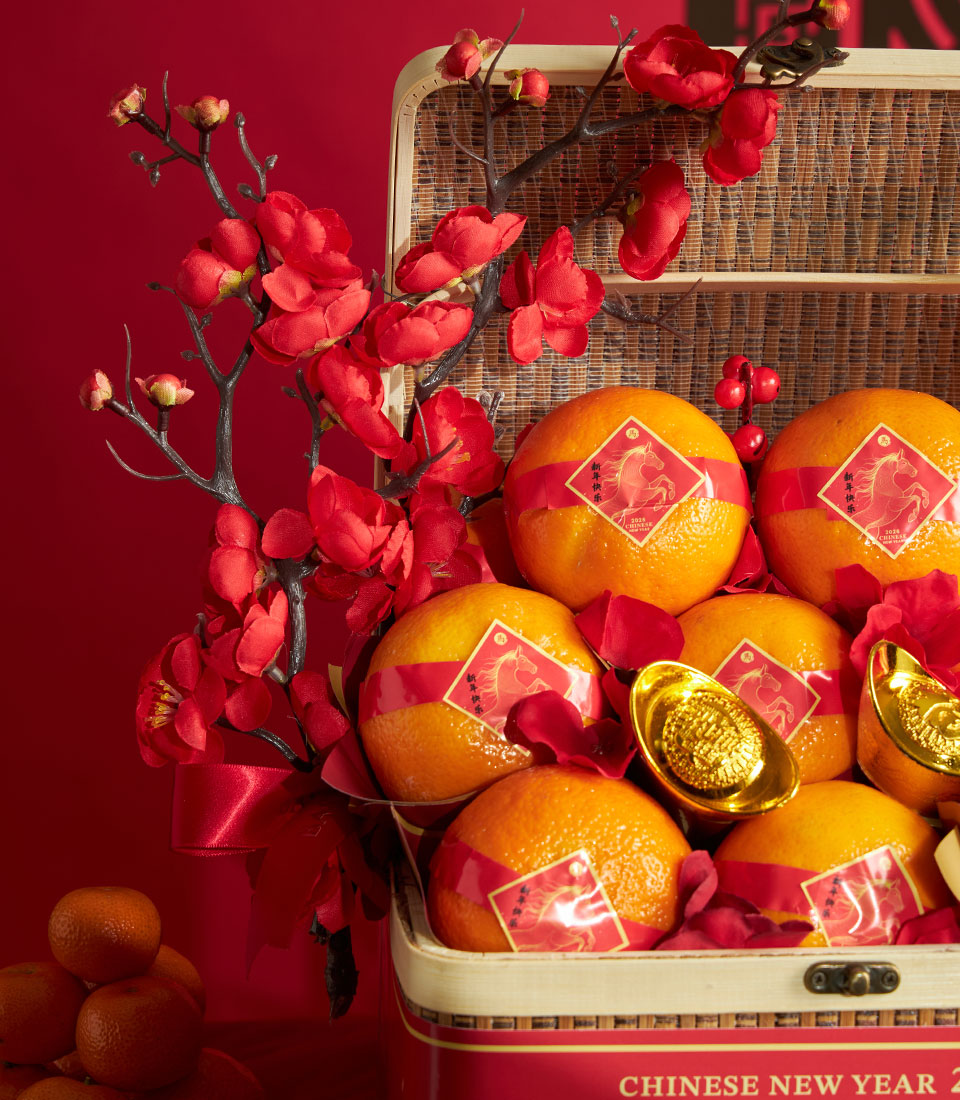 Mandarin orange gift basket with red festive ribbons, gold accents, and plum blossoms for Chinese New Year