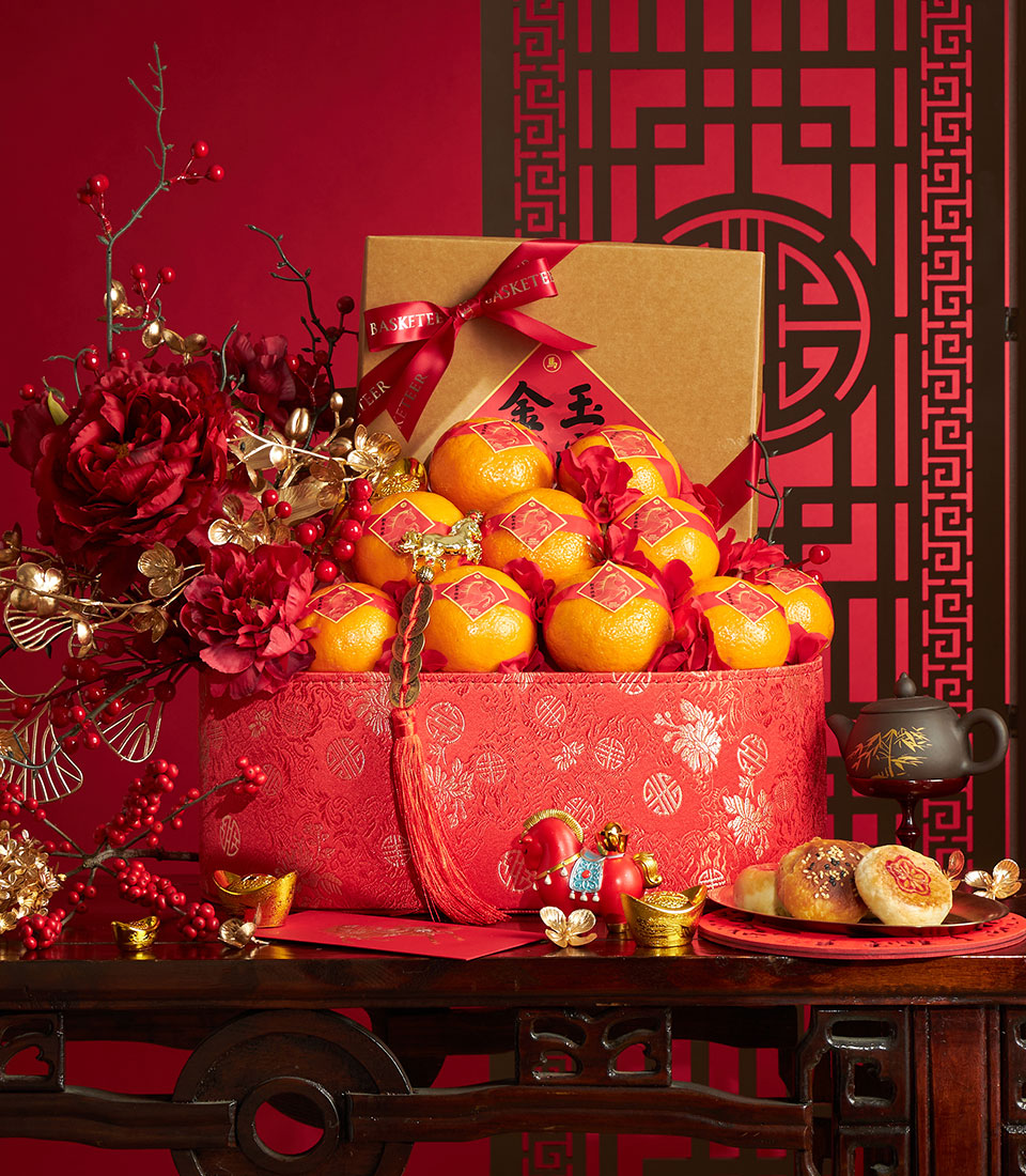 Luxury Chinese New Year gift basket with mandarin oranges, red peonies, pastries, and gold accents