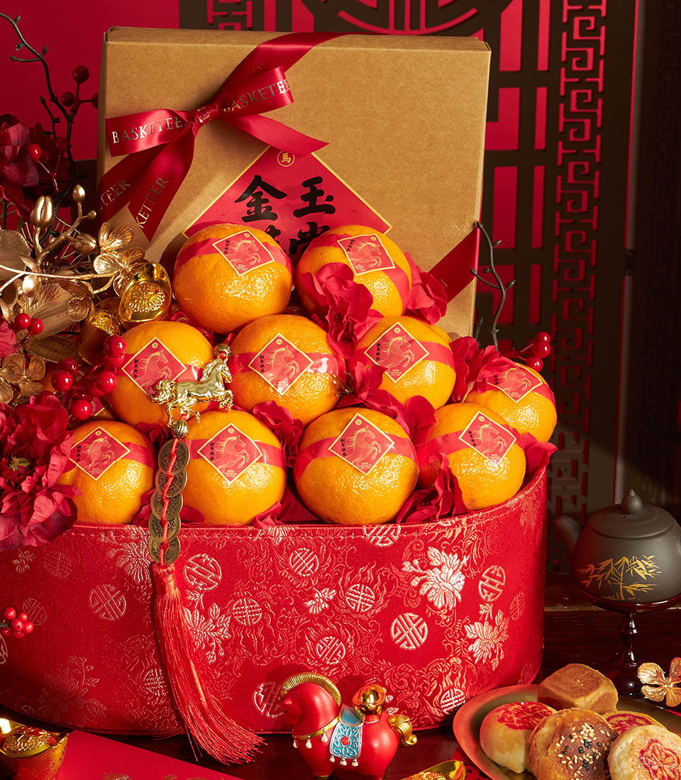 Red mandarin orange gift basket with gold auspicious symbols, pastries, and Chinese New Year celebration items in festive