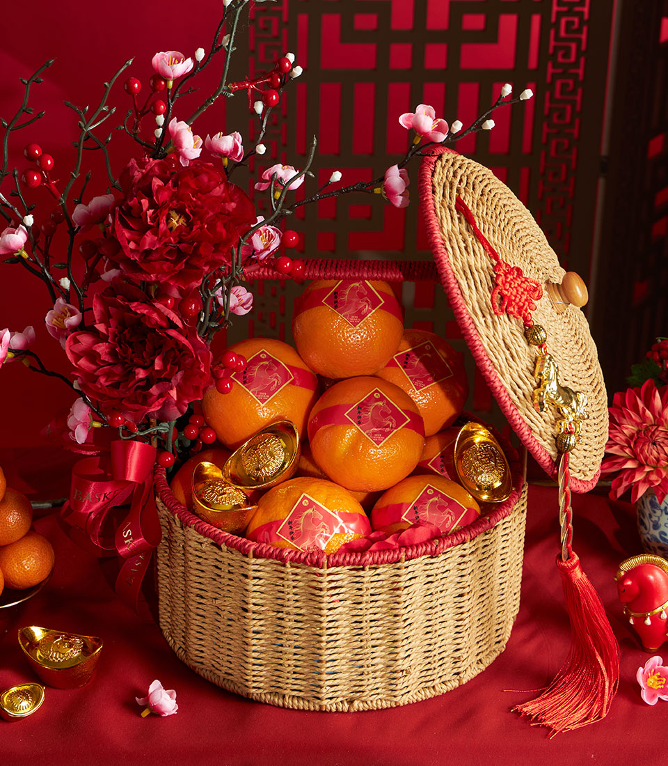 Festive Chinese New Year mandarin orange basket with artificial red peonies, golden ornaments, and traditional red