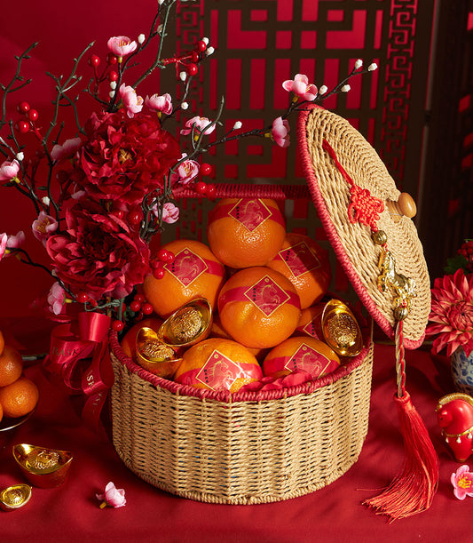 Festive Chinese New Year mandarin orange basket with artificial red peonies, golden ornaments, and traditional red