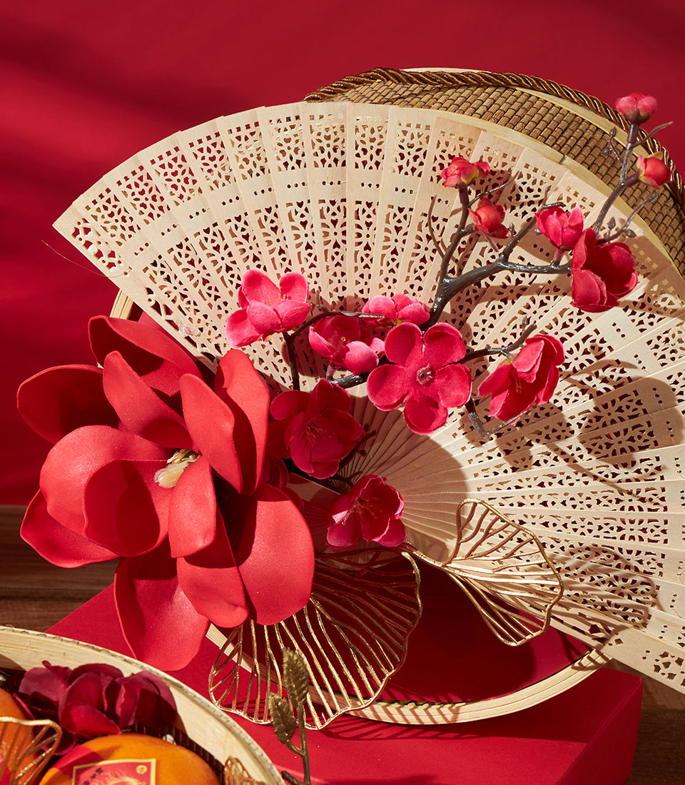 Festive red mandarin orange gift basket with carved wooden fans and silk flowers for Chinese New Year
