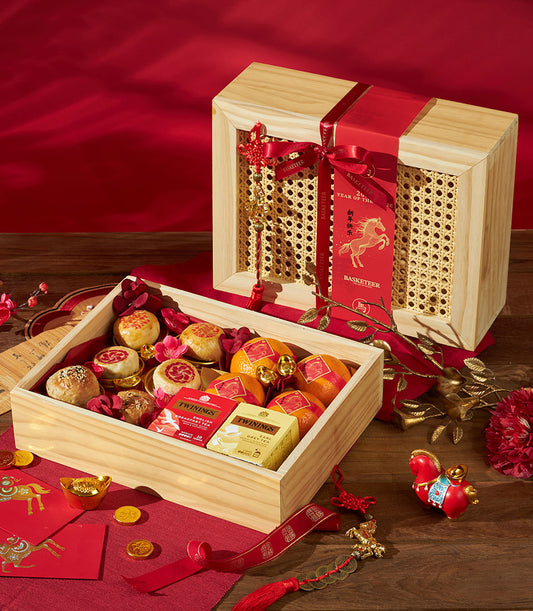 Mandarin oranges, tea, and pastries in festive wooden Chinese New Year gift box with red and gold ribbon