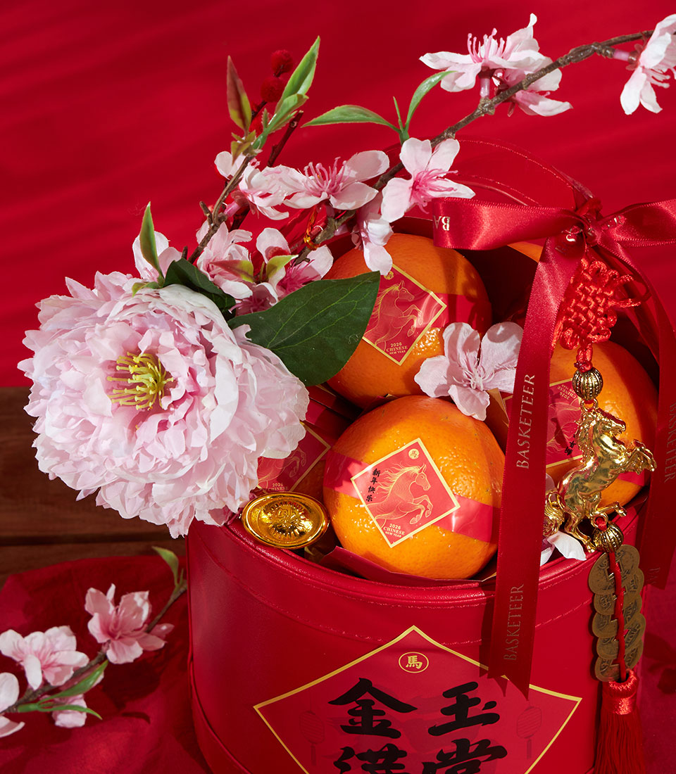Premium mandarin oranges with cherry blossoms and gold charms in red festive gift container for Chinese New Year prosperity