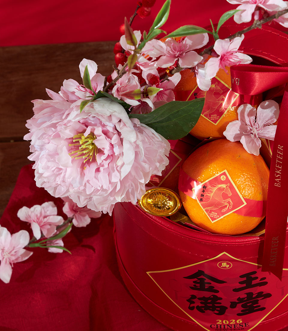 Premium mandarin oranges in red woven gift basket with gold accents, peonies, and cherry blossoms for Chinese New Year