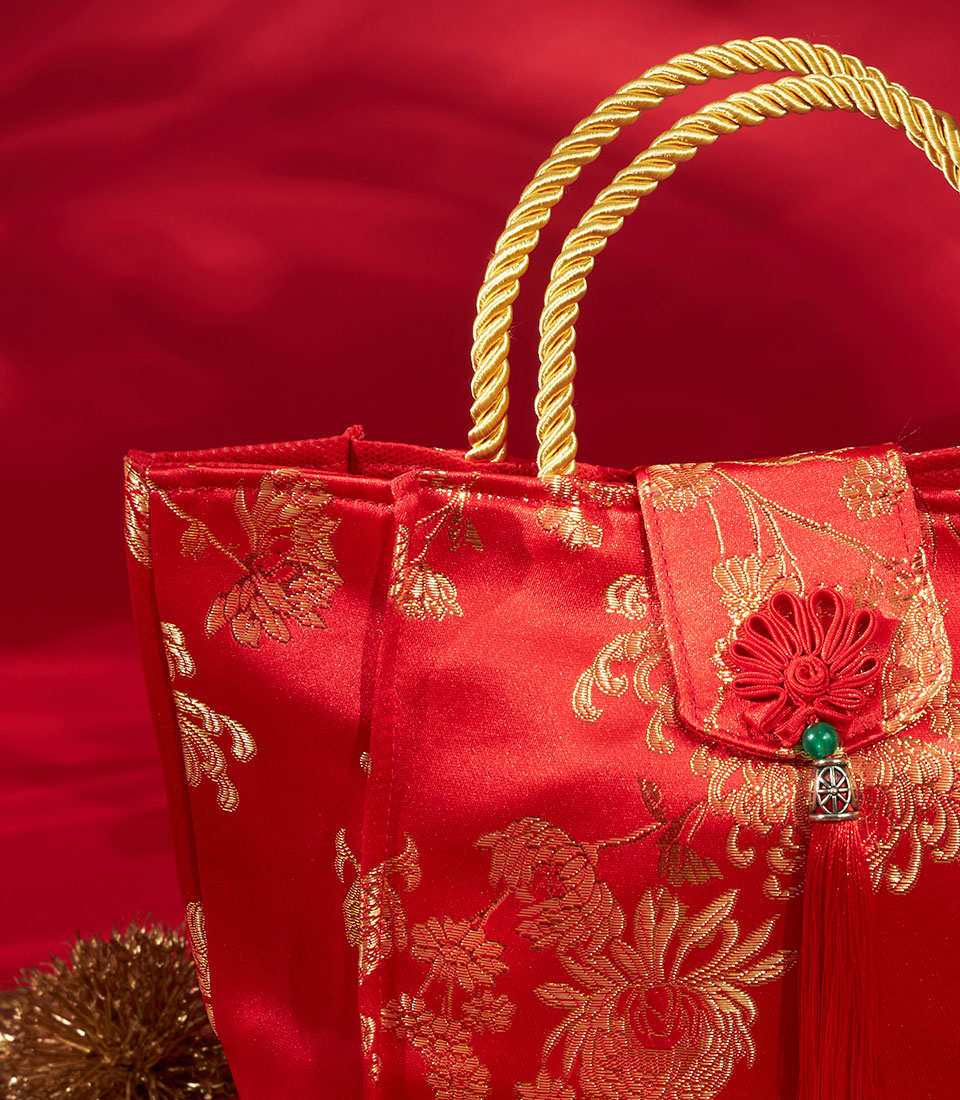 Red satin gift bag with gold floral embroidery and twisted handles for Chinese New Year celebrations