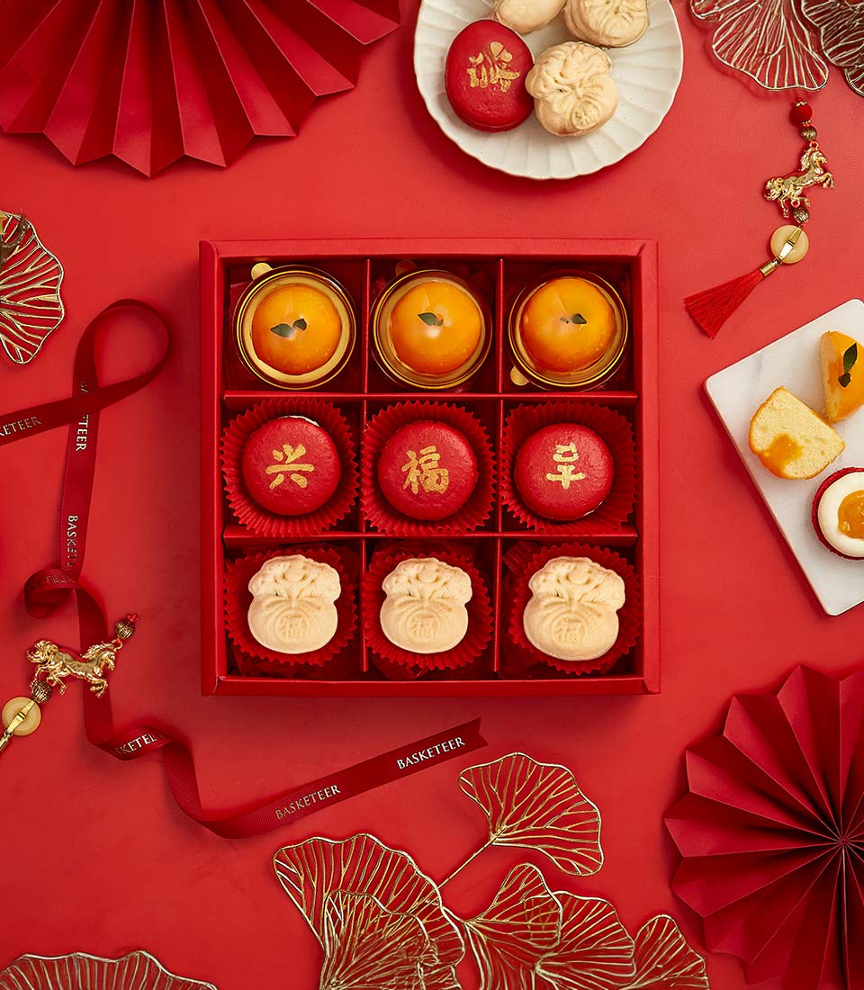 Auspicious red and gold dessert gift box with macarons, pastries, and lucky ingot-shaped treats for Chinese New Year