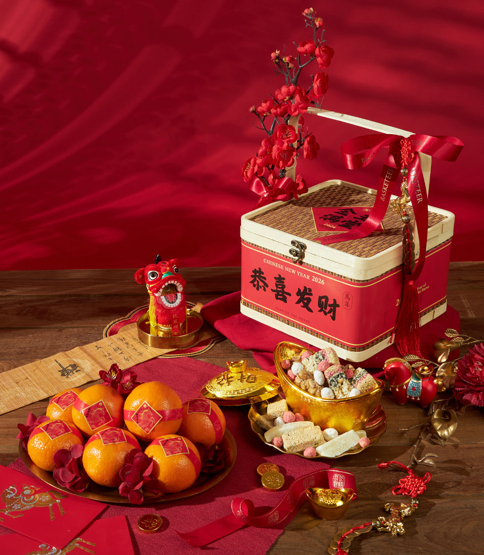 Mandarin oranges and Chinese festive sweets gift set with red silk ribbon, bamboo box, and traditional New Year decorations
