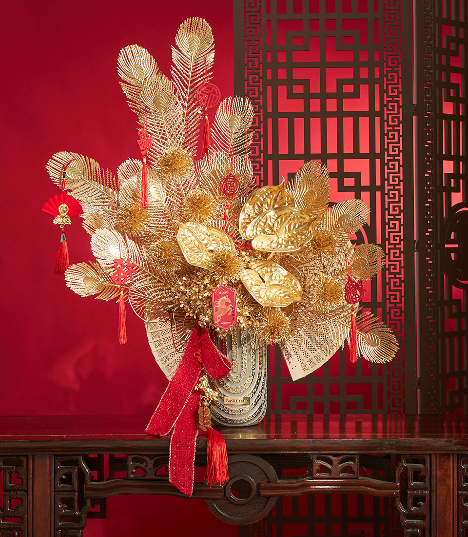 Golden artificial flower arrangement with red accents and Chinese New Year ornaments in elegant vase