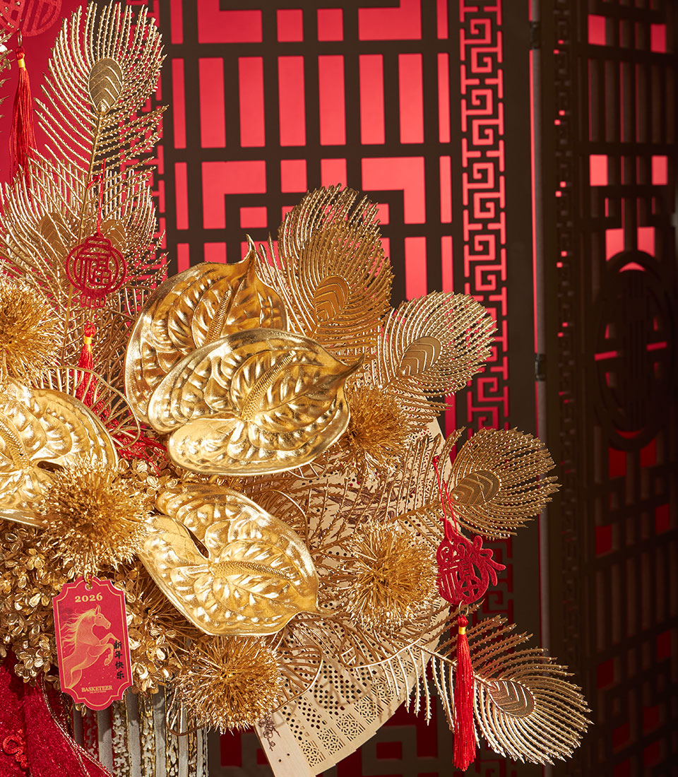 Golden anthurium and peacock feather arrangement with festive red accents for Chinese New Year celebrations
