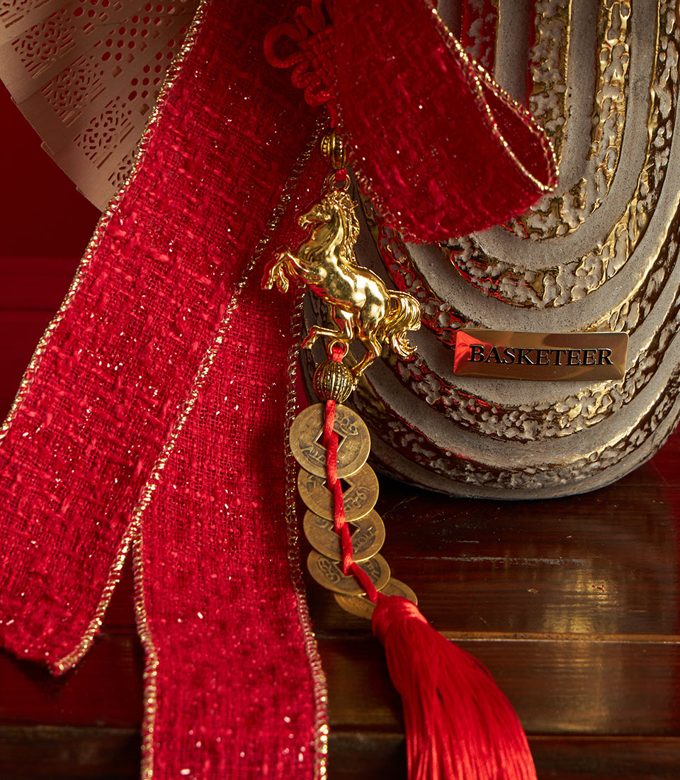 Chinese New Year golden artificial flower arrangement with red silk ribbon, lucky coins charm, and ornamental ceramic vessel