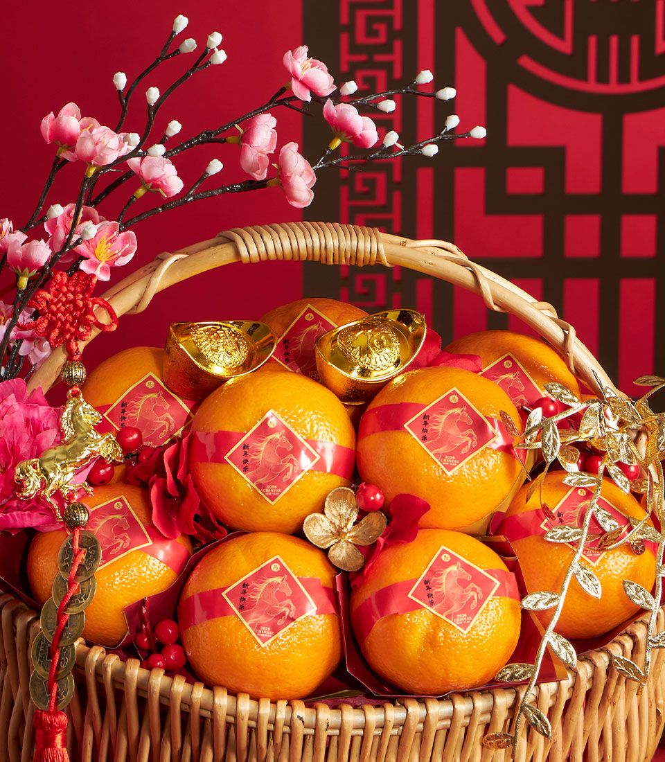 Festive wicker basket overflowing with bright mandarin oranges tied in red ribbons, gold ingots, and Chinese New Year