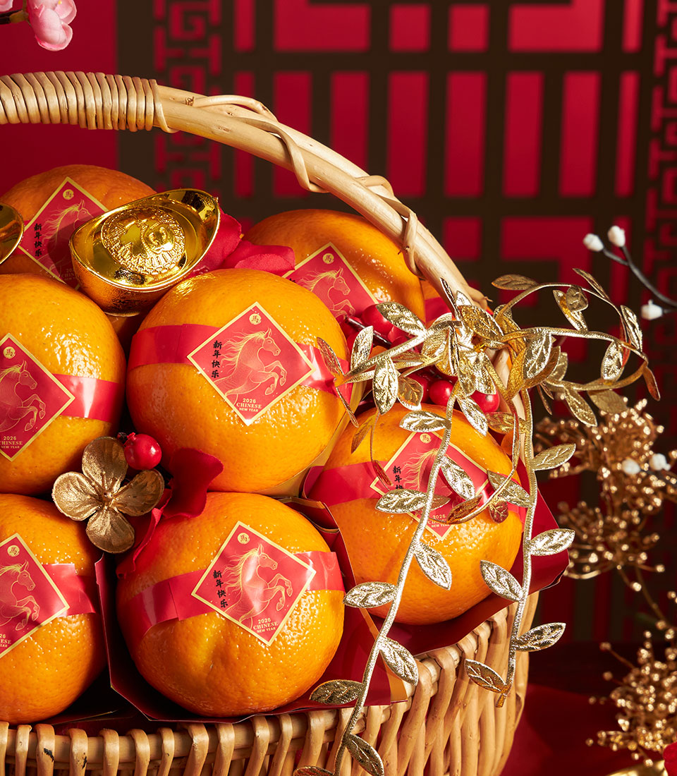 Woven wicker basket filled with red-wrapped mandarin oranges, gold ingots, and festive Chinese New Year accents with gold