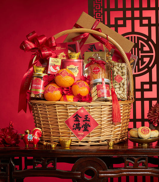 Woven wicker gift basket with red satin bow filled with mandarin oranges, gourmet treats, and gold prosperity decorations