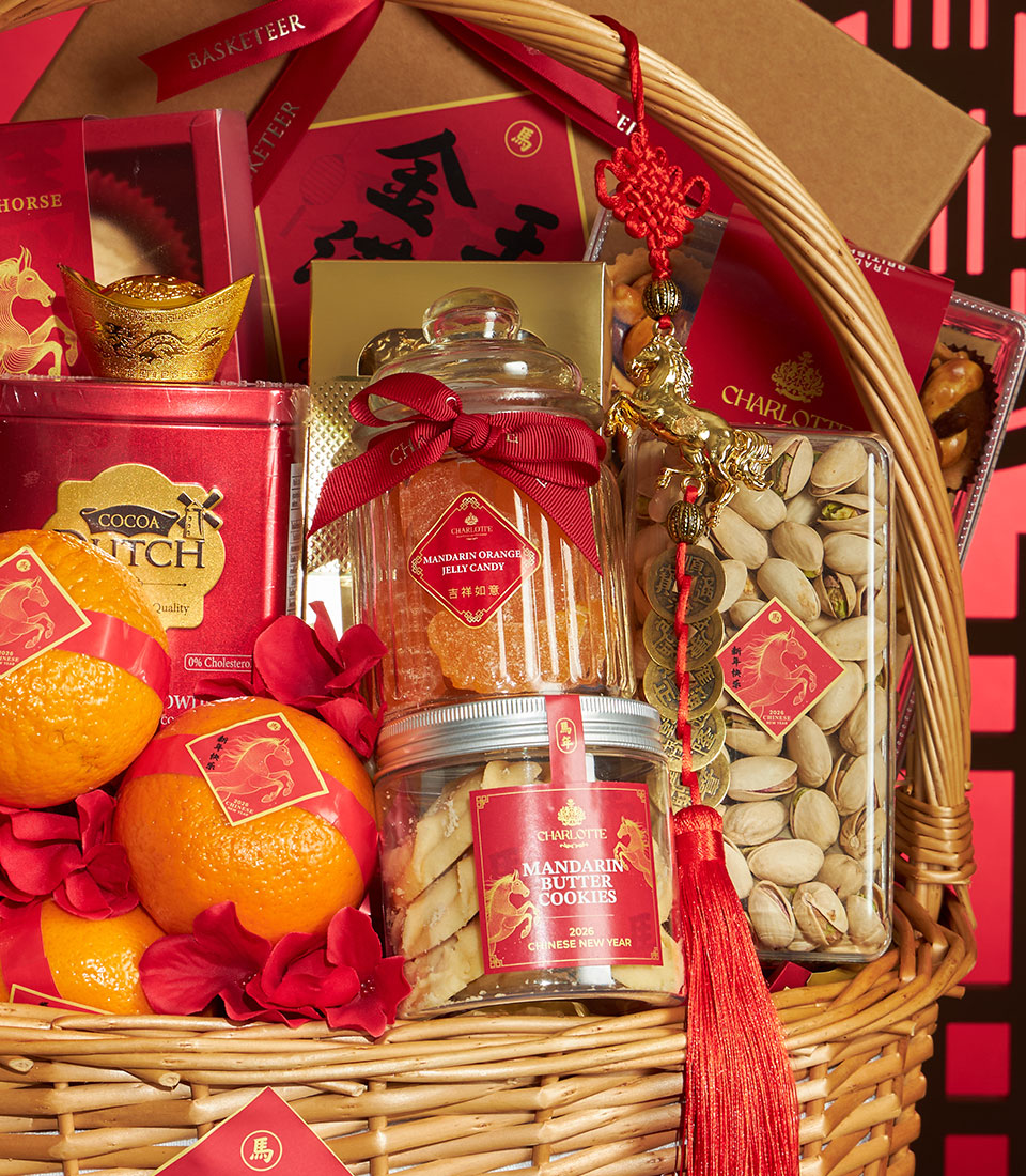 Light brown woven basket with red ribbon-wrapped mandarins, mandarin jelly candy, butter cookies, pistachios, Dutch cocoa,