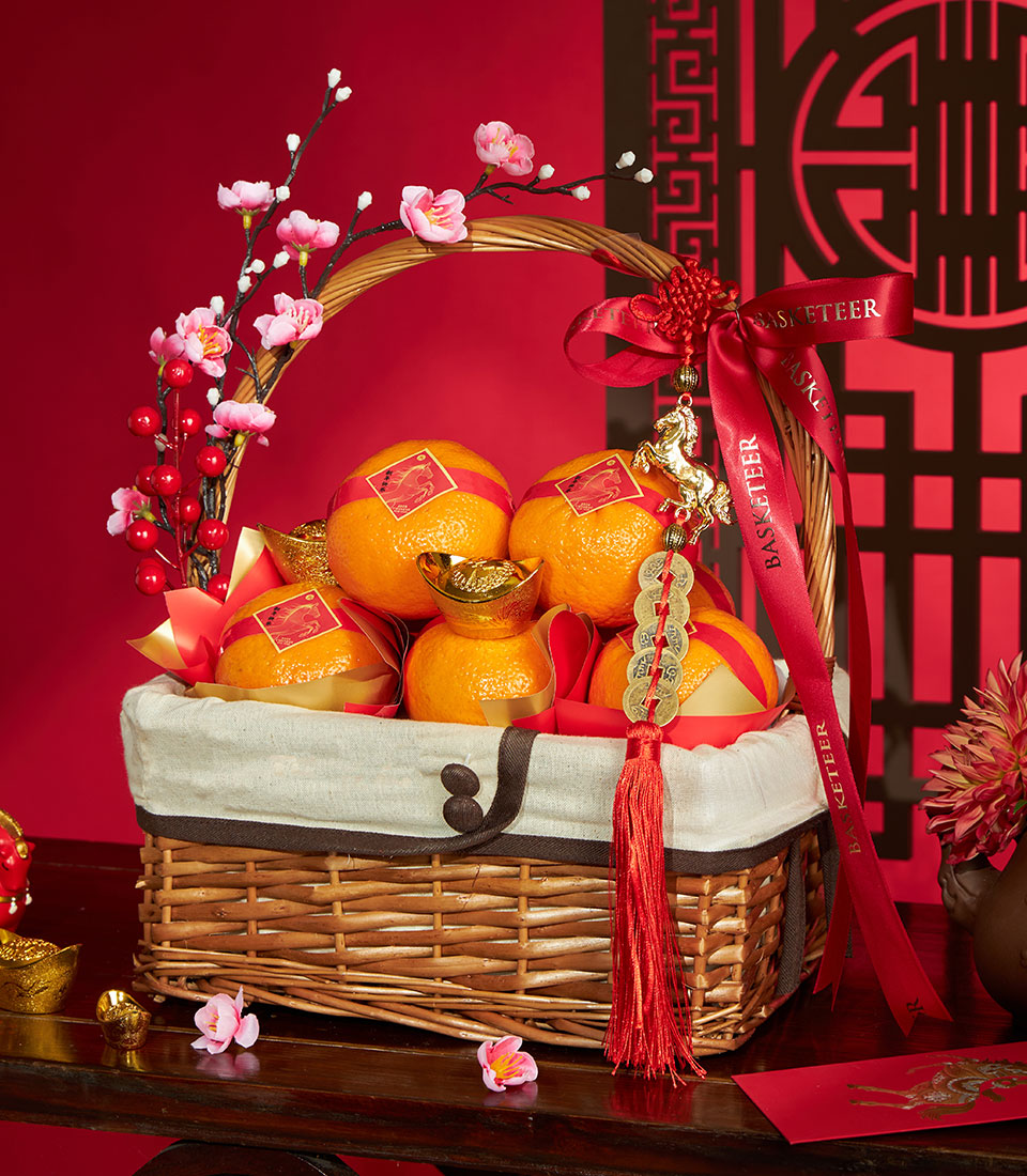 Festive Chinese New Year mandarin orange gift basket with red satin ribbon, golden prosperity ingots, and cherry blossom