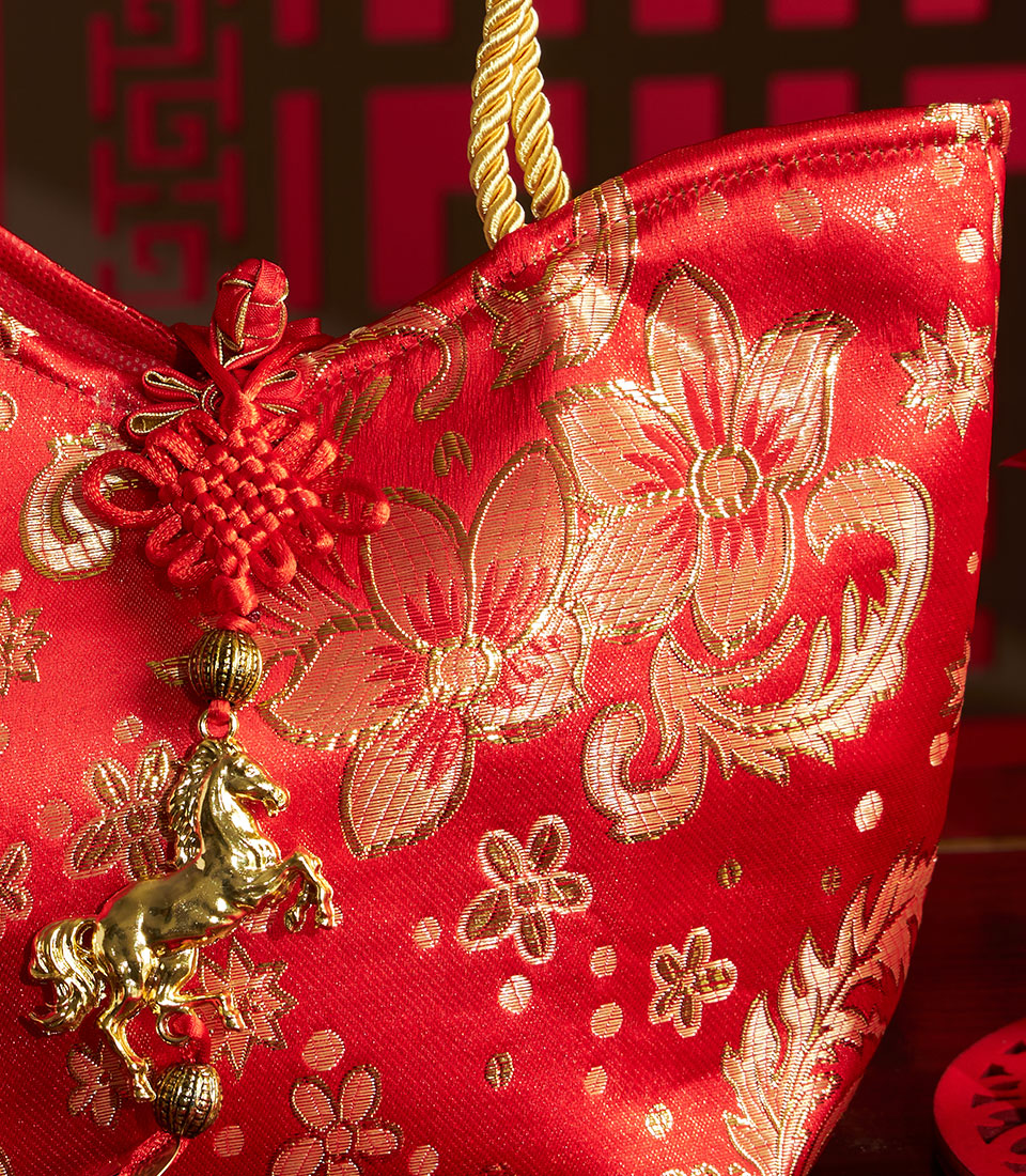 Red silk gift bag with gold floral patterns and traditional Chinese knot tassel for lunar new year