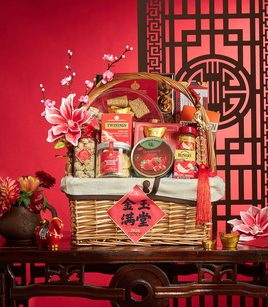 Woven wicker basket with gourmet treats, tea, and cookies for Chinese New Year, styled with red flowers, gold accents, and