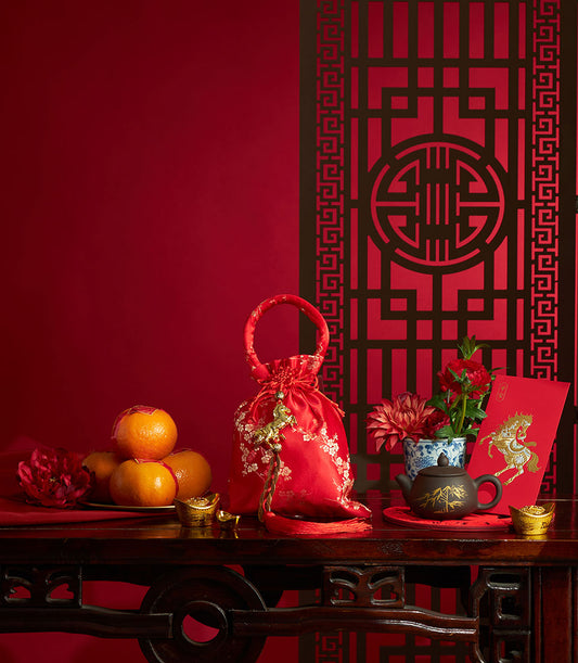 Chinese New Year mandarin orange gift bag with red satin, white embroidery, and golden horse charm, surrounded by tea,