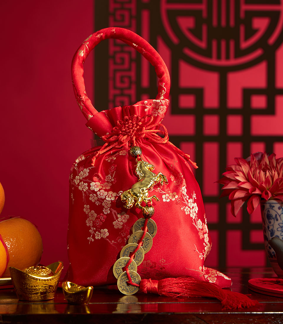 Red satin gift pouch with mandarin oranges, gold ingots, and Chinese coins for Lunar New Year celebration