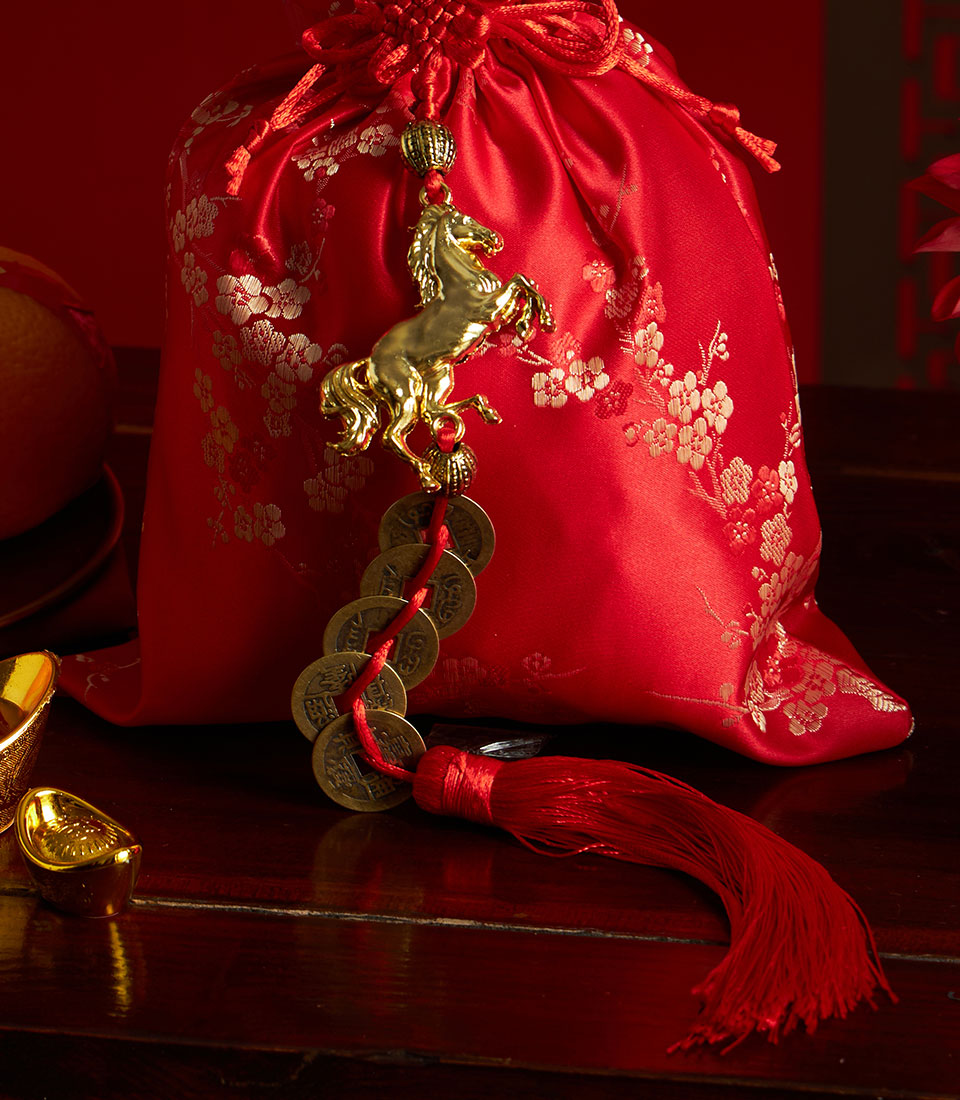Red satin Chinese New Year gift bag with gold floral charm, coins, and tassel for festive celebrations