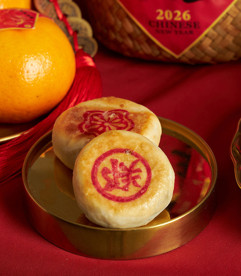 Luxury Chinese New Year gift hamper with mandarin oranges, golden pastries, and auspicious symbols on red silk backdrop