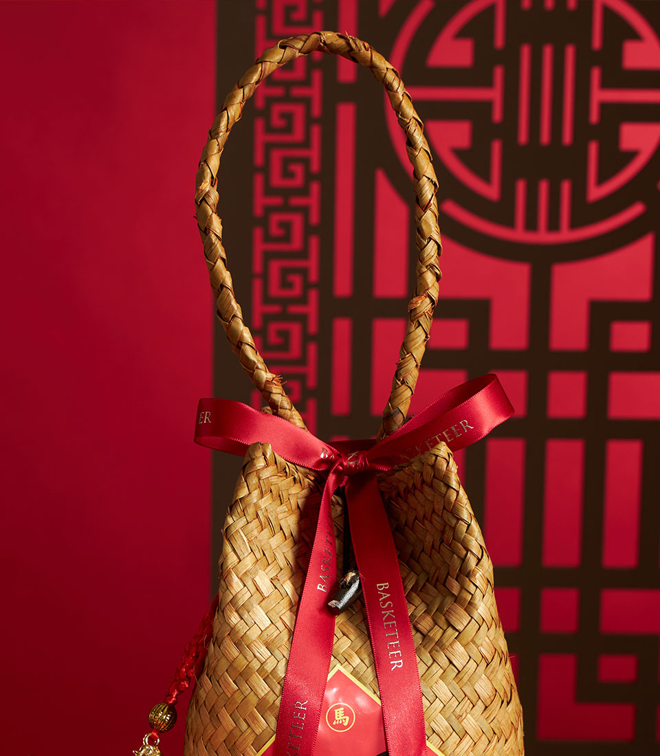 Woven straw gift bag with red satin ribbon and gold Chinese character charm for Lunar New Year