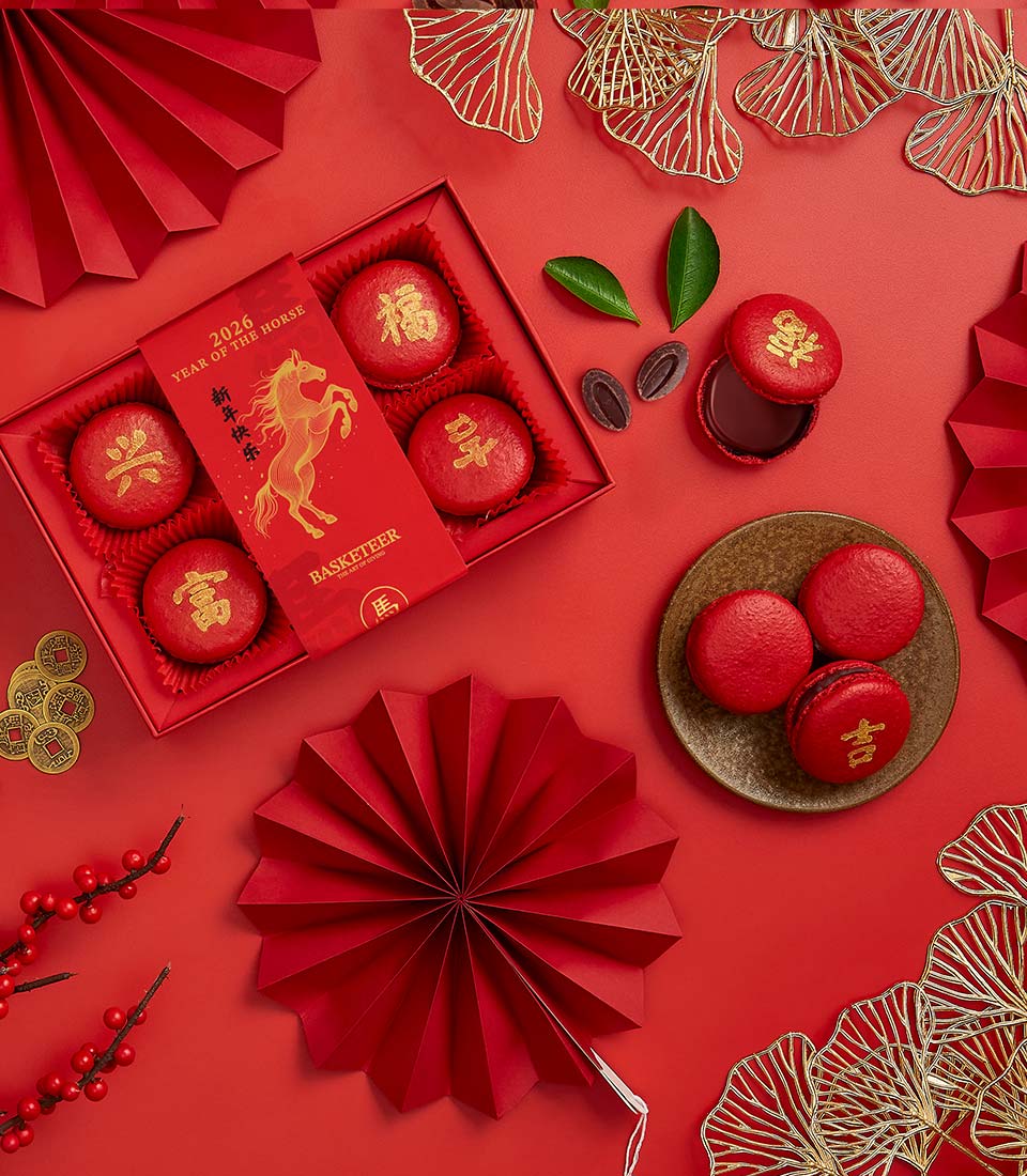 Red macarons with gold Chinese characters, festive gift box with Year of the Horse sleeve for Lunar New Year celebrations