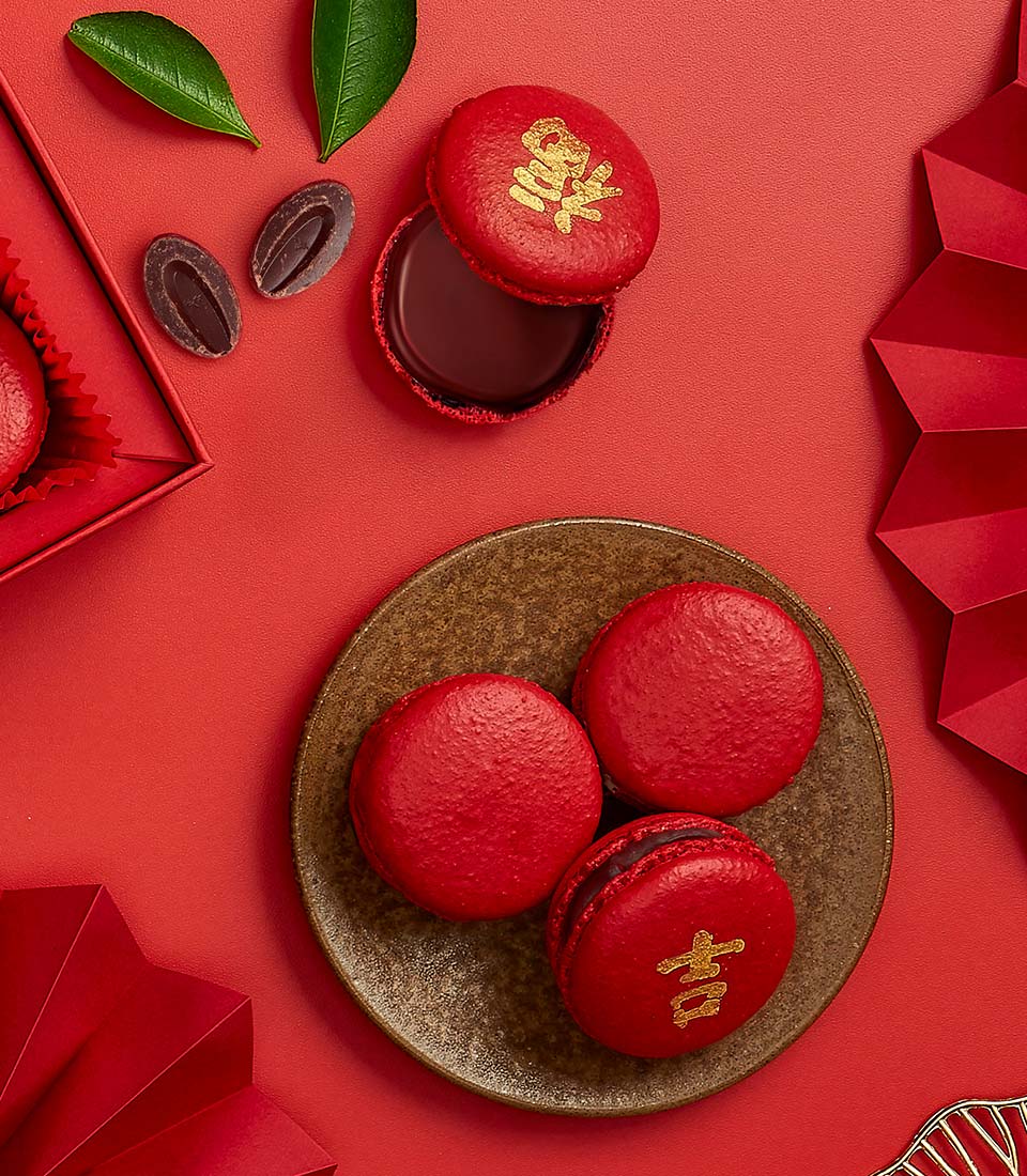 Red macarons with chocolate filling and gold Chinese characters, festive new year gift arrangement on red background