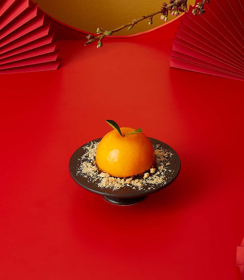 Golden Fortune mandarin chiffon cake with leaf detail on dark pedestal, Chinese New Year gift set