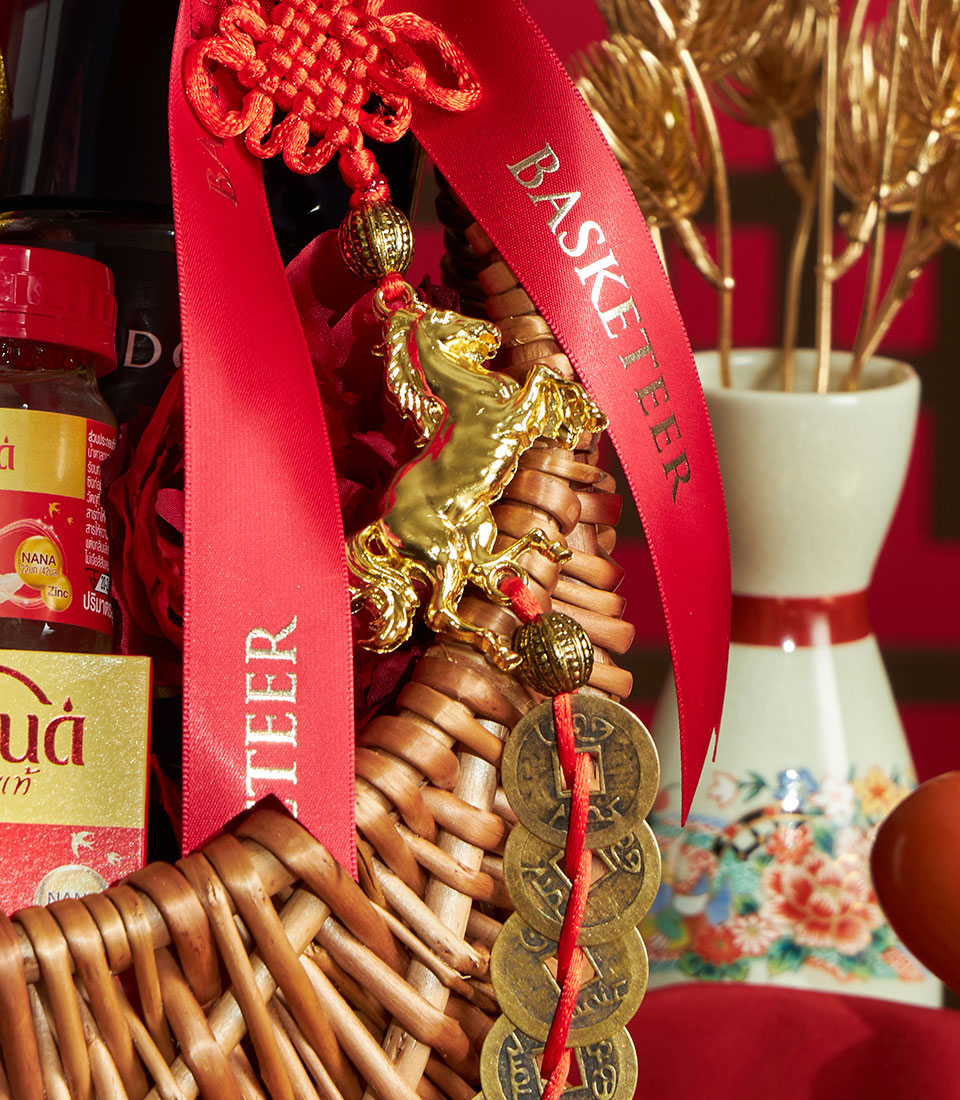 Premium wicker gift basket with red ribbon, Chinese knot charm, and gold coins for Chinese New Year celebrations