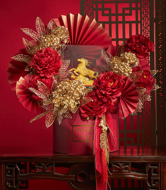 Basketeer premium hamper delivery Thailand: striking red floral arrangement with gold accents and a golden horse figurine. A luxurious corporate gift Bangkok.