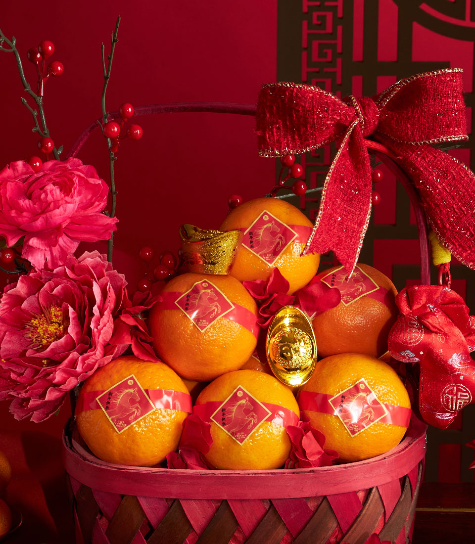 Festive Chinese New Year mandarin orange basket with red artificial peonies, gold ingots, and lucky red bow