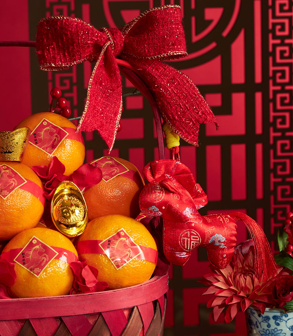 Vibrant Chinese New Year mandarin orange gift basket with gold ingots, red bow, and horse charm decoration