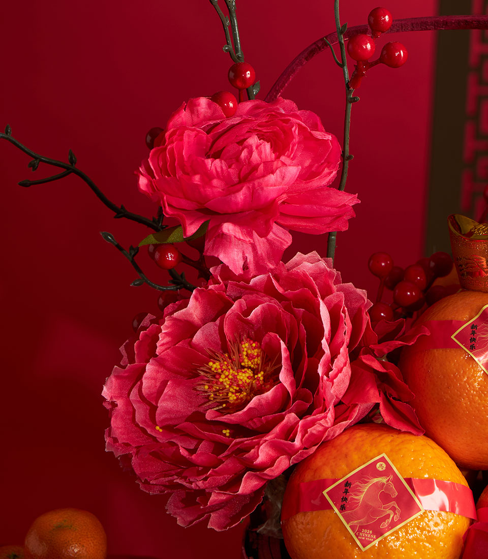 Vibrant pink peonies and mandarin oranges with red ribbons for Chinese New Year celebration