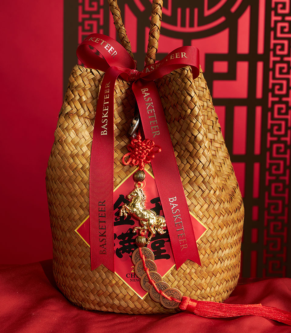 Woven straw gift basket with red satin ribbons, Chinese knot charm, and golden horse figurine for Chinese New Year