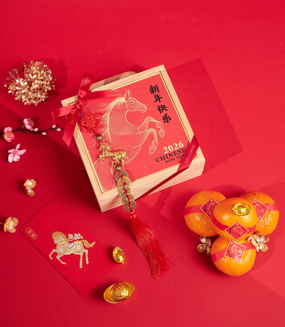 Wooden Chinese New Year gift box with mandarin oranges, red envelope, gold coins and cherry blossoms on red background