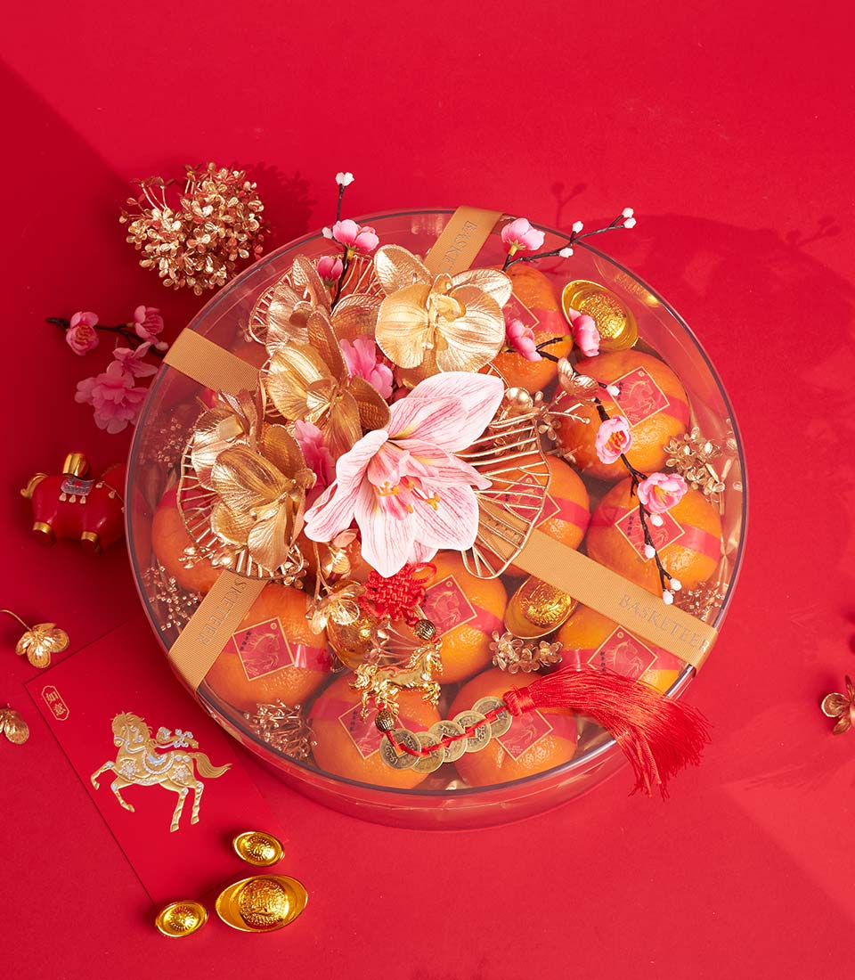 Festive Chinese New Year mandarin orange gift box with orchids, amaryllis, and gold accents on red background
