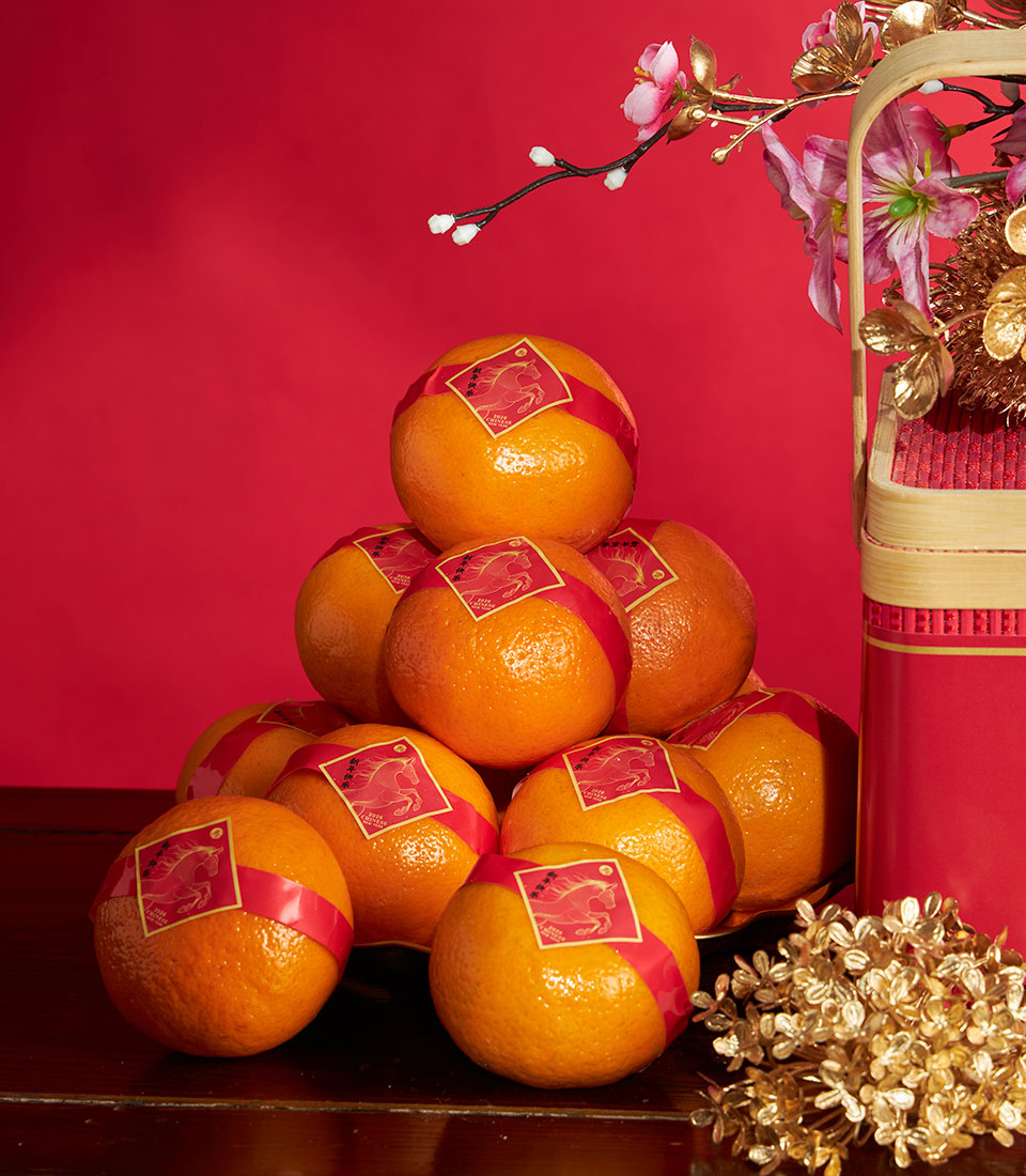 Mandarin orange gift box with red ribbons and golden horse labels, paired with bamboo basket and pink gold flowers for