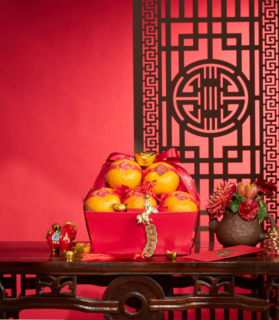 Festive red gift box with fresh mandarins, gold ingots, and silk ribbons for Chinese New Year