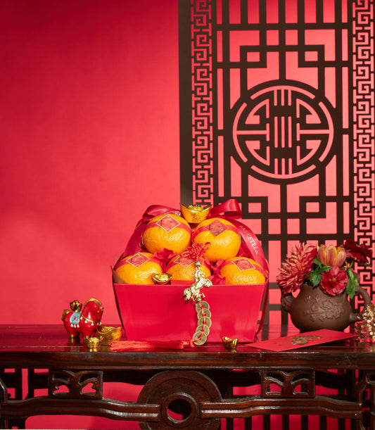 Festive red gift box with fresh mandarins, gold ingots, and silk ribbons for Chinese New Year