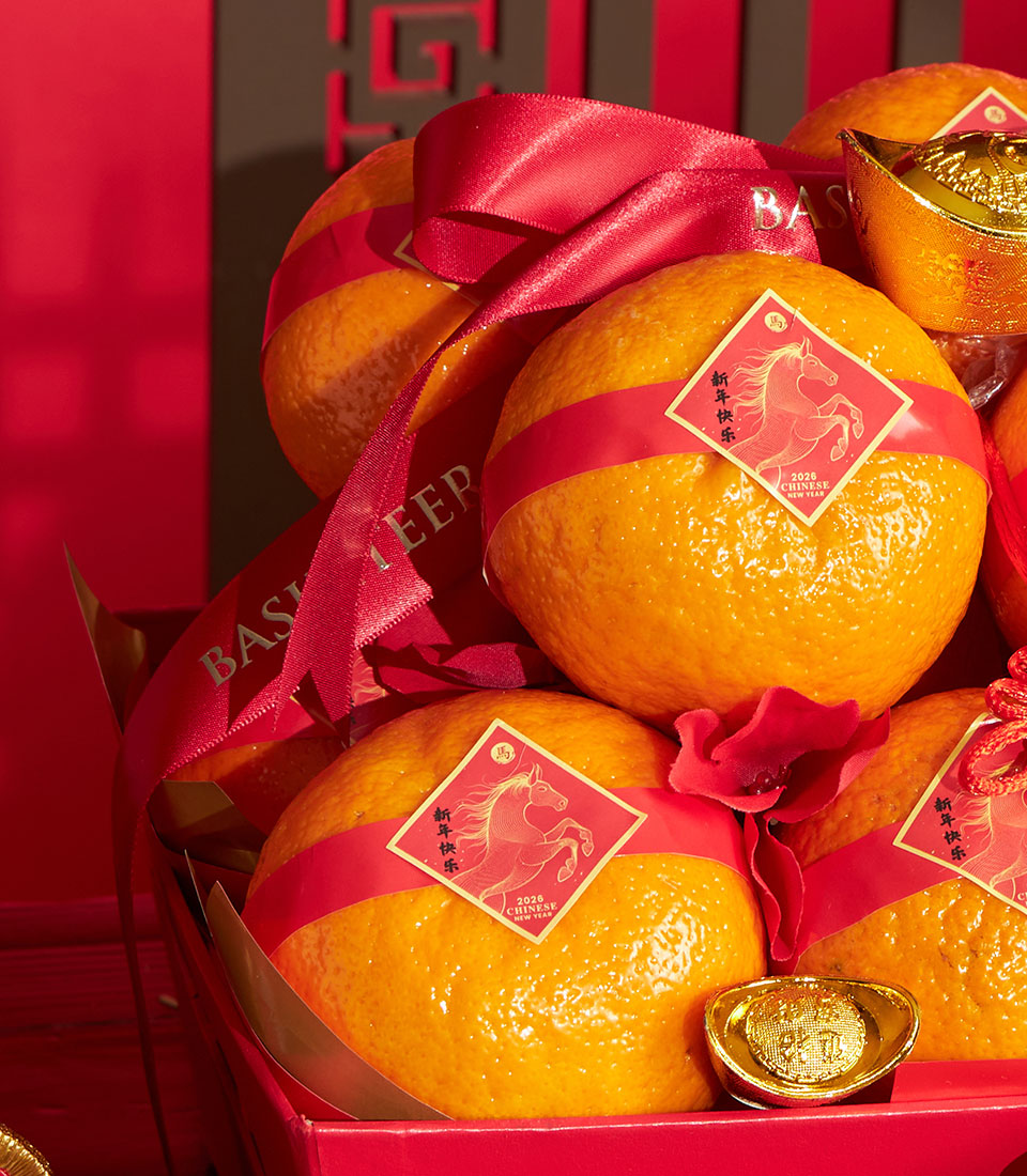 Festive mandarin orange gift box with red ribbon, gold ingots, and Chinese New Year lucky symbols