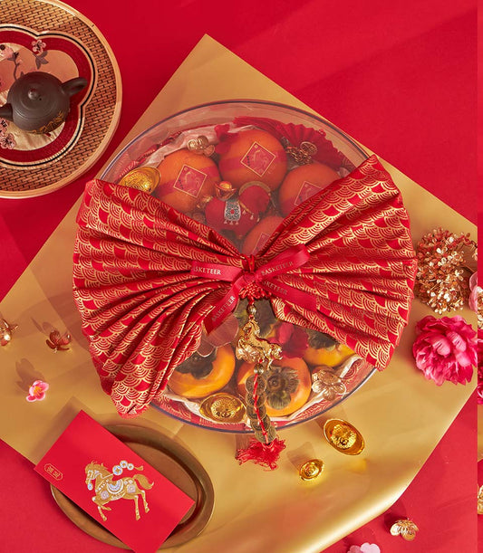 Festive Chinese New Year mandarin orange and persimmon gift basket with red ribbon bow, gold accents, and prosperity charms